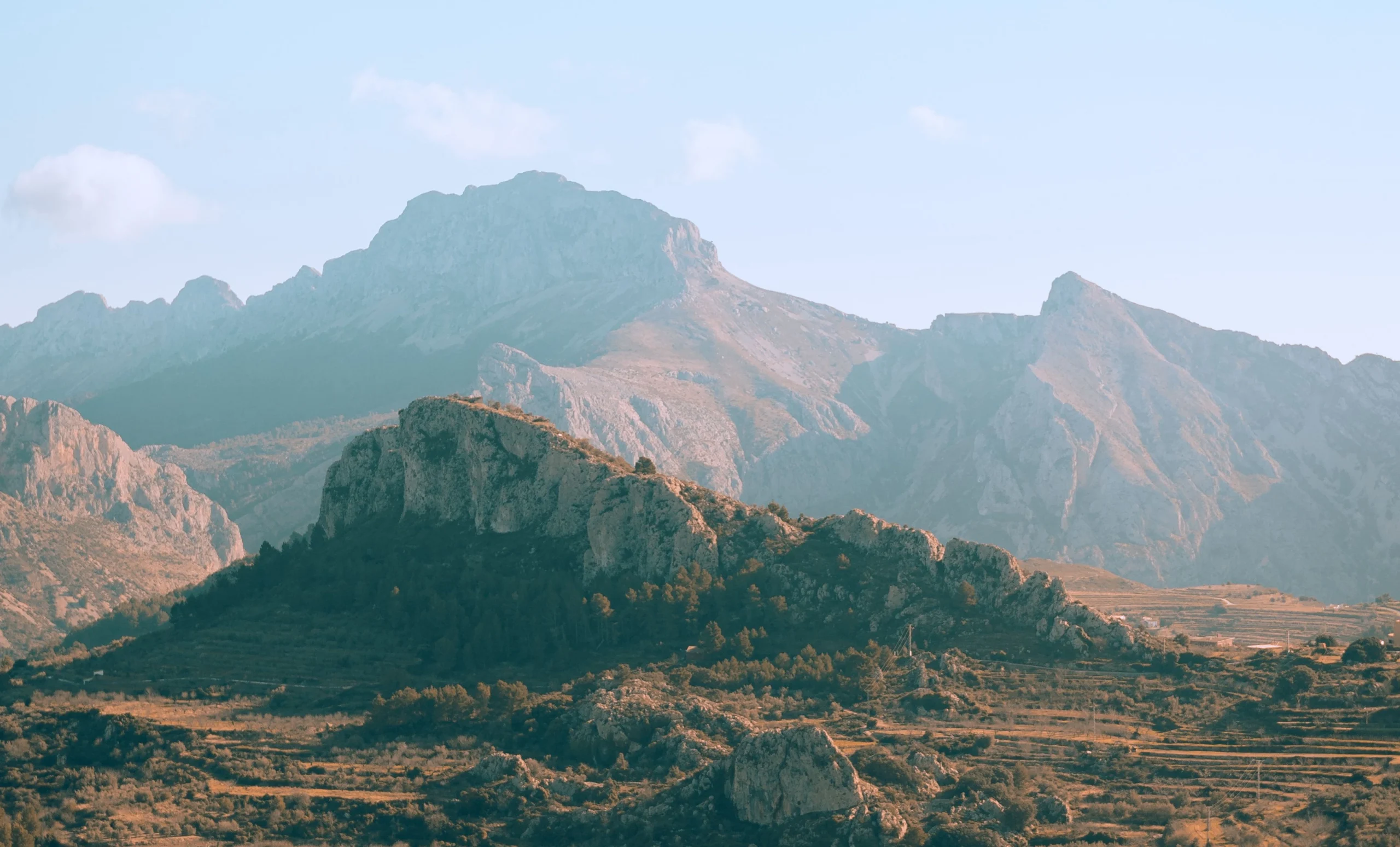 Sunlit rugged mountain range with rocky foreground